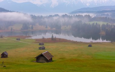 Orman kenarında dağ çayırında küçük bir kulübe, Geroldsee arka planda Karwendel Dağları gündoğumunda, Kaltenbrunn, Yukarı Bavyera, Almanya