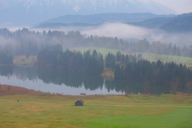 Orman kenarında dağ çayırında küçük bir kulübe, Geroldsee arka planda Karwendel Dağları gündoğumunda, Kaltenbrunn, Yukarı Bavyera, Almanya