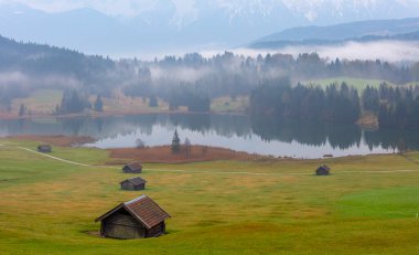 Orman kenarında dağ çayırında küçük bir kulübe, Geroldsee arka planda Karwendel Dağları gündoğumunda, Kaltenbrunn, Yukarı Bavyera, Almanya