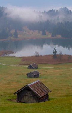 Orman kenarında dağ çayırında küçük bir kulübe, Geroldsee arka planda Karwendel Dağları gündoğumunda, Kaltenbrunn, Yukarı Bavyera, Almanya