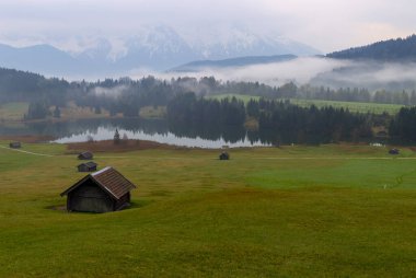 Orman kenarında dağ çayırında küçük bir kulübe, Geroldsee arka planda Karwendel Dağları gündoğumunda, Kaltenbrunn, Yukarı Bavyera, Almanya