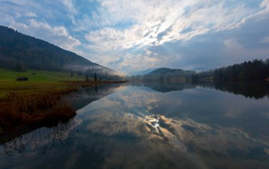 Orman kenarında dağ çayırında küçük bir kulübe, Geroldsee arka planda Karwendel Dağları gündoğumunda, Kaltenbrunn, Yukarı Bavyera, Almanya