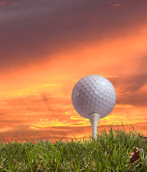 Golf ball on tee against a beautiful sunset — Stock Photo, Image