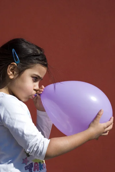 Девушка взрывает воздушный шар — стоковое фото