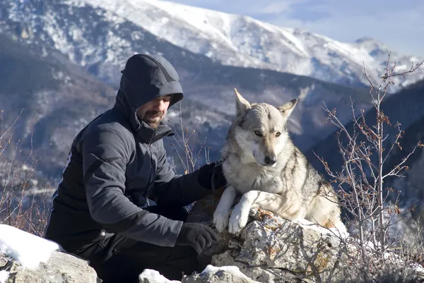 Человек с собачьей прогулкой в зимних горах — стоковое фото