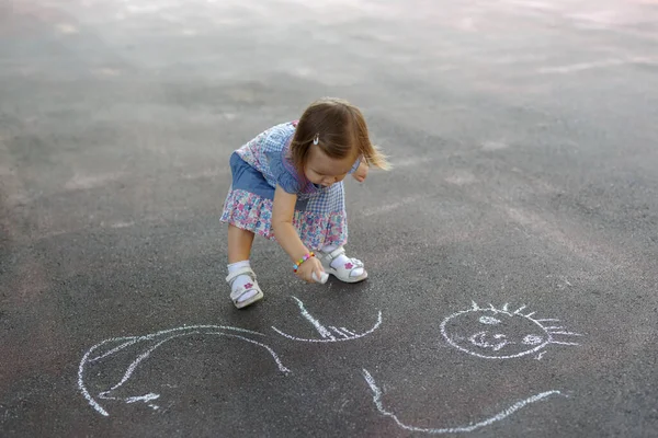 一个小女孩在人行道上用彩色粉笔潦草乱画的头像照片 图库图片