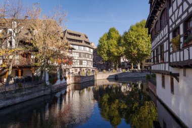 Strasbourg, Fransa - 25 Ekim 2021: Kanal boyunca Petite France bölgesindeki yarı keresteli evlere bir manzara. Strasbourglar, kaldırım taşı sokakları, kanallar ve iyi korunmuş yarım ahşap binalarla tanınan canlı turist merkezleridir.