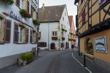 Eguisheim, Fransa - 24 Ekim 2021: Doğu Fransa 'nın Alsace bölgesindeki iyi korunmuş yarı ağaçlandırılmış binaları çevreleyen tarihi Eguisheim köyündeki kaldırım taşı caddesi boyunca bakın