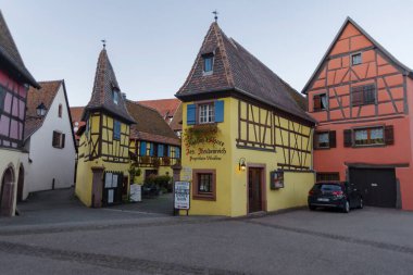 Eguisheim, Fransa - 24 Ekim 2021: Doğu Fransa 'nın Alsace bölgesindeki iyi korunmuş yarı ağaçlandırılmış binaları çevreleyen tarihi Eguisheim köyündeki kaldırım taşı caddesi boyunca bakın
