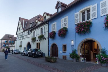 Eguisheim, Fransa - 24 Ekim 2021: Doğu Fransa 'nın Alsace bölgesindeki iyi korunmuş yarı ağaçlandırılmış binaları çevreleyen tarihi Eguisheim köyündeki kaldırım taşı caddesi boyunca bakın