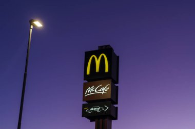 Imperia, İtalya - 12 Ocak 2022: McDonald 's ve McCafe logoları Imperia, İtalya' da gece fast-food hamburger restoranının önünde