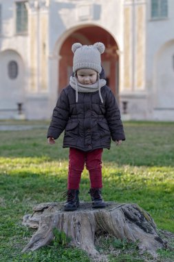 Girl playing on old tree stump in a public park