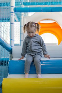 Child girl climbing down ramp in soft play centre