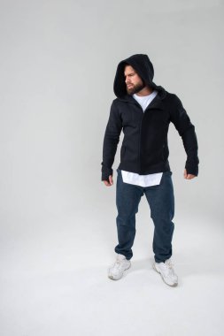 Siyah kapüşonlu, sakallı erkek model stüdyoda.