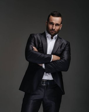 Stüdyoda çapraz elleri olan takım elbiseli yakışıklı bir iş adamı.