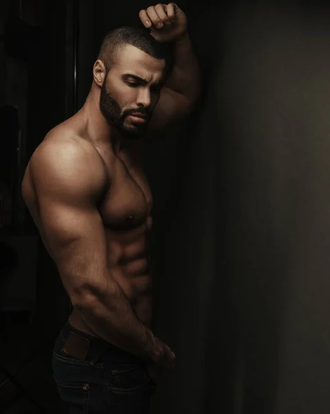 Gömleksiz, sakalsız, kot pantolonlu bir fitness adamının siyah portresi.