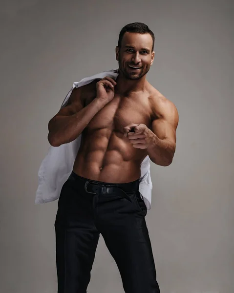 Motivated and happy shirtless handsome man with white shirt pointing his finger at camera