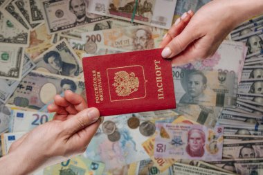 Farklı para birimlerinde Rus pasaportu tutan iki el.