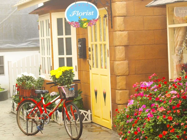 This vintage red girls bicycle has beautiful yellow flowers in a basket on the front of the bike — Stock Photo, Image