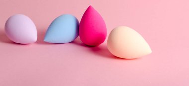 makeup sponge blender colored on pink background. Makeup tool for applying and blending products . High quality photo. Copy text photo
