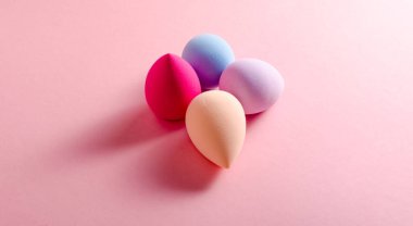 makeup sponge blender colored on pink background. Makeup tool for applying and blending products . High quality photo. Copy text photo