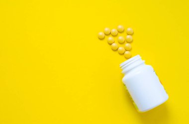 Sarı arka plandaki kavanozdan sarı haplar. Yüksek kalite fotoğraf