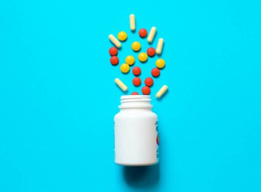 Mavi arka plandaki bir kavanozdan bir sürü renkli hap. Yüksek kalite fotoğraf