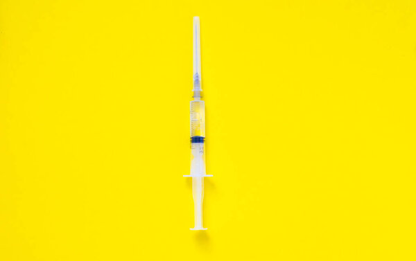 syringe on a yellow background minimalism. High quality photo