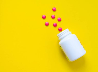 Sarı arka plandaki kavanozdan kırmızı haplar. Yüksek kalite fotoğraf