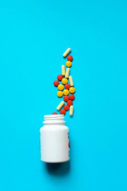 Mavi arka plandaki bir kavanozdan bir sürü renkli hap. Yüksek kalite fotoğraf