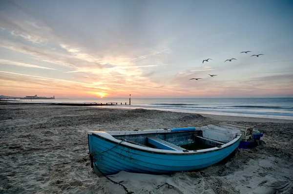 ビーチの日の出で青いボート — ストック写真