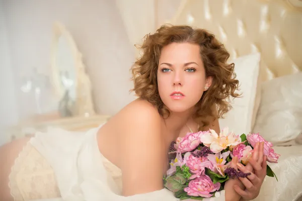 Schöne junge Plus-Size-Frau mit blauen Augen im Bett liegend — Stockfoto
