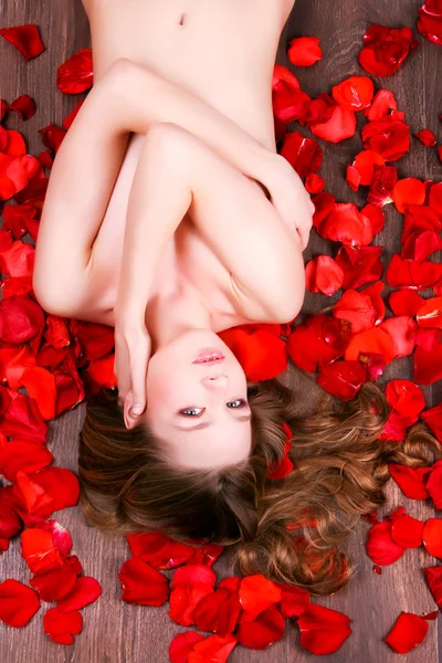 Frau liegt in Rosenblättern — Stockfoto