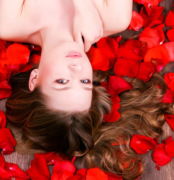 Girl laying in petals of roses — Stock Photo, Image