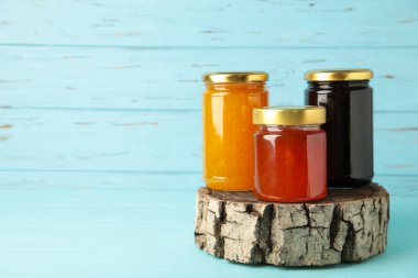 Mavi arka plandaki kavanozda ev yapımı meyve reçeli.