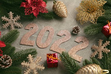 Köknar ağaçları, köknar kozalakları, Noel süslemeleri ve 2022 rakamlarıyla Noel arkaplanı. Griye yeni yıl konsepti. Üst görünüm