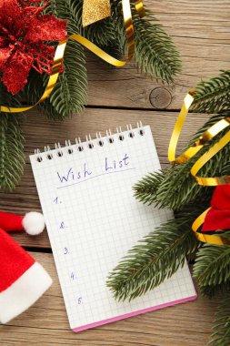 Noel süsleri ve gri ahşap arka planda dilek listesi olan bir defter. Planlama konsepti. Yeni Yıl Kompozisyonu