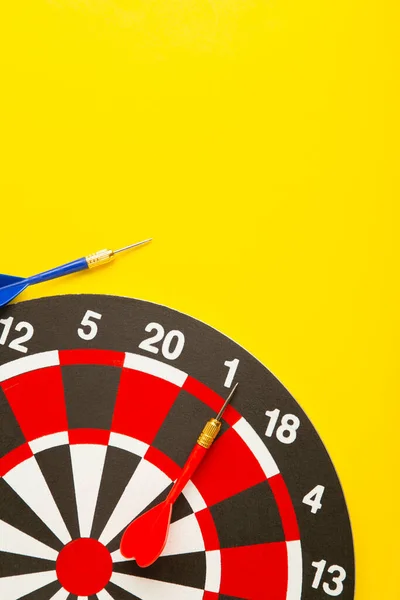 Dart board with darts on yellow background. Top view.