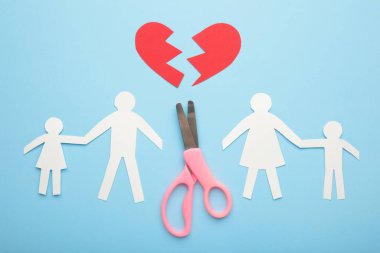 Mavi arka planda ailenin kağıt kesme makası. Parçalanmış aile kavramı, boşanma. Üst görünüm