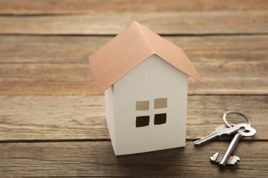 Gri arkaplanda fotokopi alanı olan kağıt ev ve anahtar. Üst görünüm