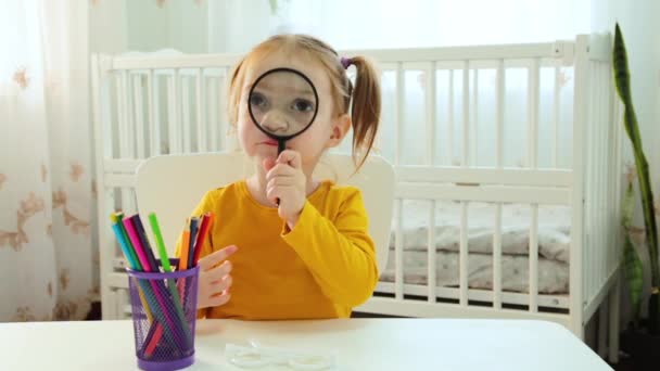 Gyönyörű Kislány Néz Egy Nagyítón Asztalnál — Stock videók