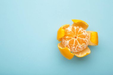 Mavi arka planda taze soyulmuş mandalina turuncusu. Üst görünüm.