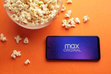 Turuncu arka plandaki akıllı telefon ekranında Hbo Max uygulaması. Filmler ve diziler için canlı yayın uygulaması. Nikolaev, Ukrayna - 20 Kasım 2021. Üst görünüm
