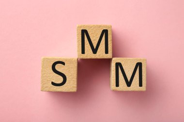 Pembe arka planda SMM sözcüğü olan tahta küpleri. Üst görünüm.