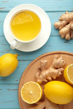 Mavi ahşap arka planda limonlu zencefil çayı ve bal. Dikey fotoğraf.