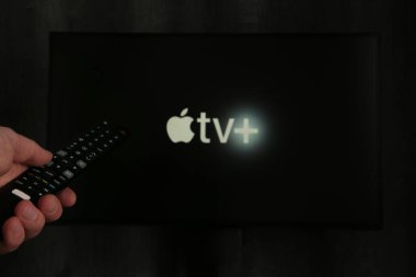 Nikolaev, Ukrayna - 20 Kasım 2021. Televizyonda yeni Apple TV ekranı olan bir adam uzaktan kumanda tutuyor. Üst görünüm.