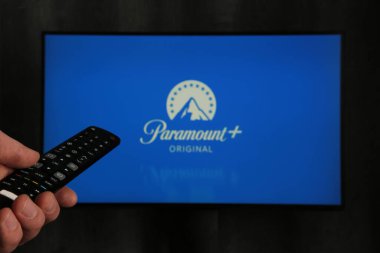 Nikolaev, Ukrayna - 20 Kasım 2021. Elinde uzaktan kumandalı bir adam ve arkasında Paramount Pictures Corporation logosu var. Üst görünüm.
