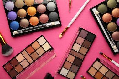 Profesyonel makyaj paleti, pembe arka planda fırçalar ve fotokopi alanı. Üst görünüm.