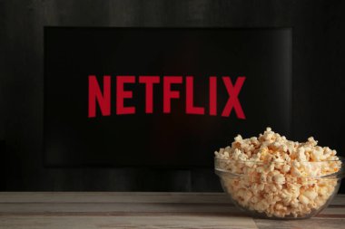 Nikolaev, Ukrayna - 20 Kasım 2021. Televizyonda patlamış mısırla Netflix izliyorum. Netflix bir çevrimiçi video yayınlama abonelik hizmeti. Üst görünüm.