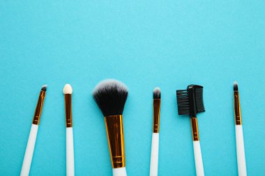 Mavi arka planda makyaj fırçaları. Üst görünüm.